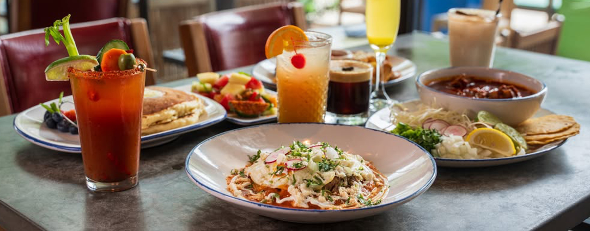 Table set with Mexican dishes, drinks, fruit, pancakes, and soup, ready for a colorful brunch at Ninfa's.