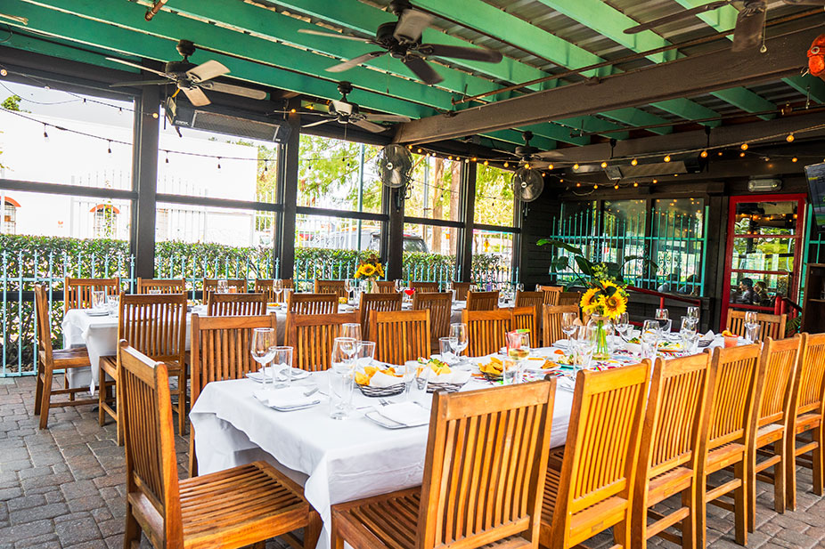Long tables with white tablecloths and wooden chairs set for dining in the Garden Patio at Ninfa's on Navigation.