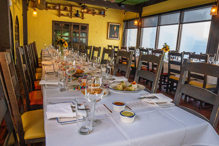 A long dining table set with plates, glasses, and food in the bright, cozy Mama's Room at Ninfa's on Navigation.