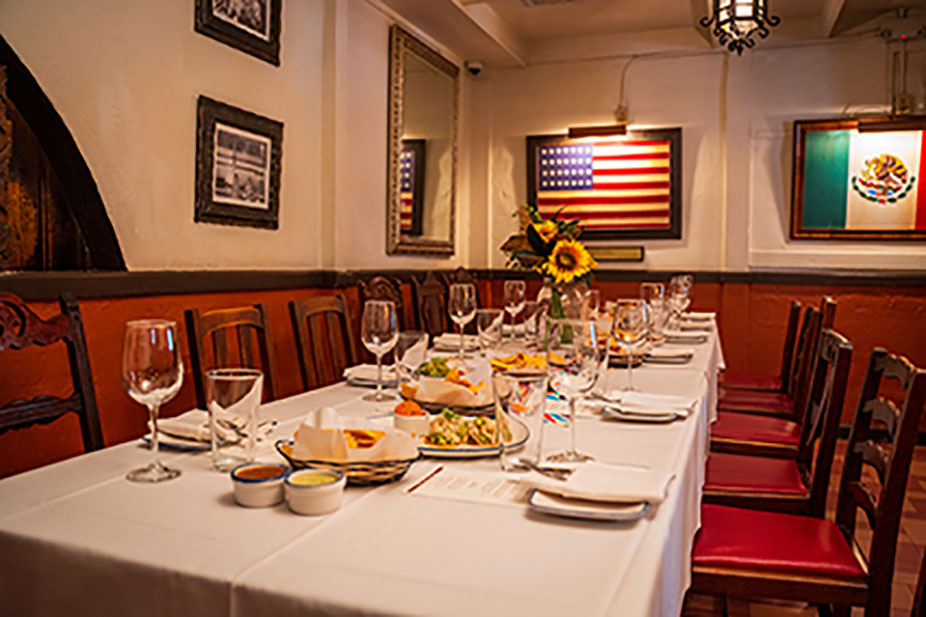 A long dining table set with food and drinks in The Original Room at Ninfa's on Navigation decorated with American and Mexican flags.