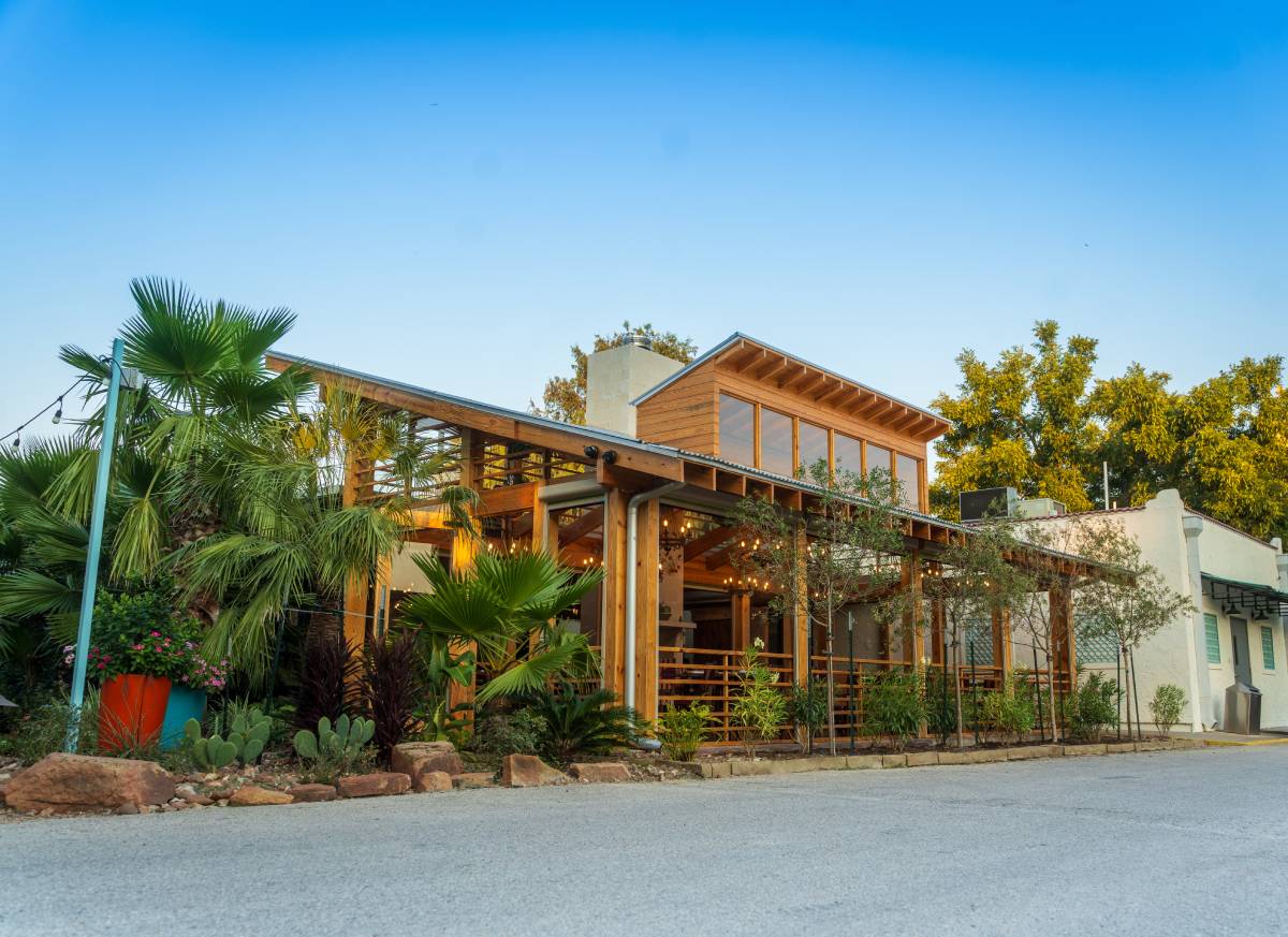 Outdoor dining table set for a meal, with colorful chairs and sunflowers, in the Front Patio at Ninfa's on Navigation.