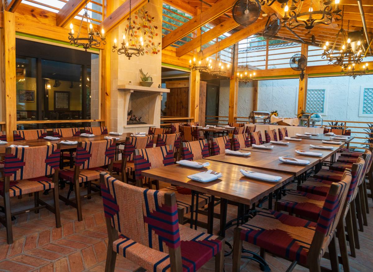 A long dining table set with glasses, plates, chips, and a sunflower centerpiece in the bright Front Patio at Ninfa's on Navigation.